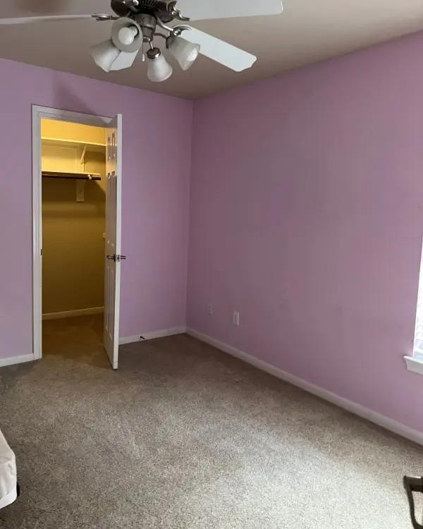 Freshly painted bedroom in a soft pink tone with a ceiling fan and an open closet doorway