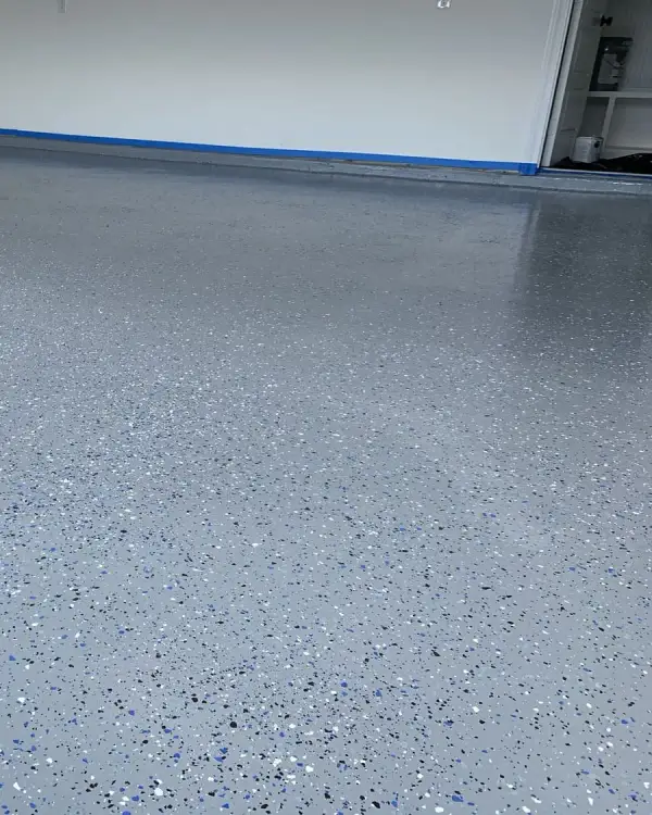 Finished grey flake epoxy garage floor with a clean blue border along the wall