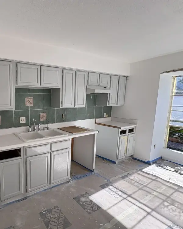 Grey kitchen cabinets installed along a wall during a kitchen remodel, countertops not yet fitted