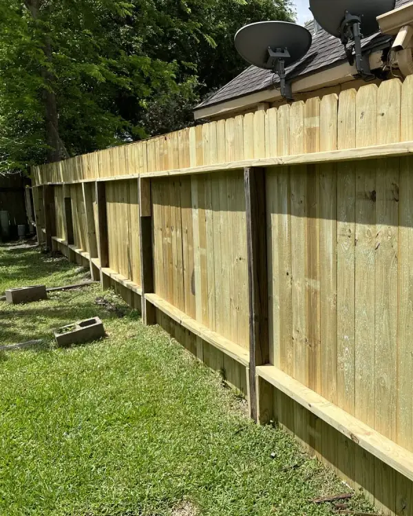 New wood privacy fence with horizontal rails running along a residential property line